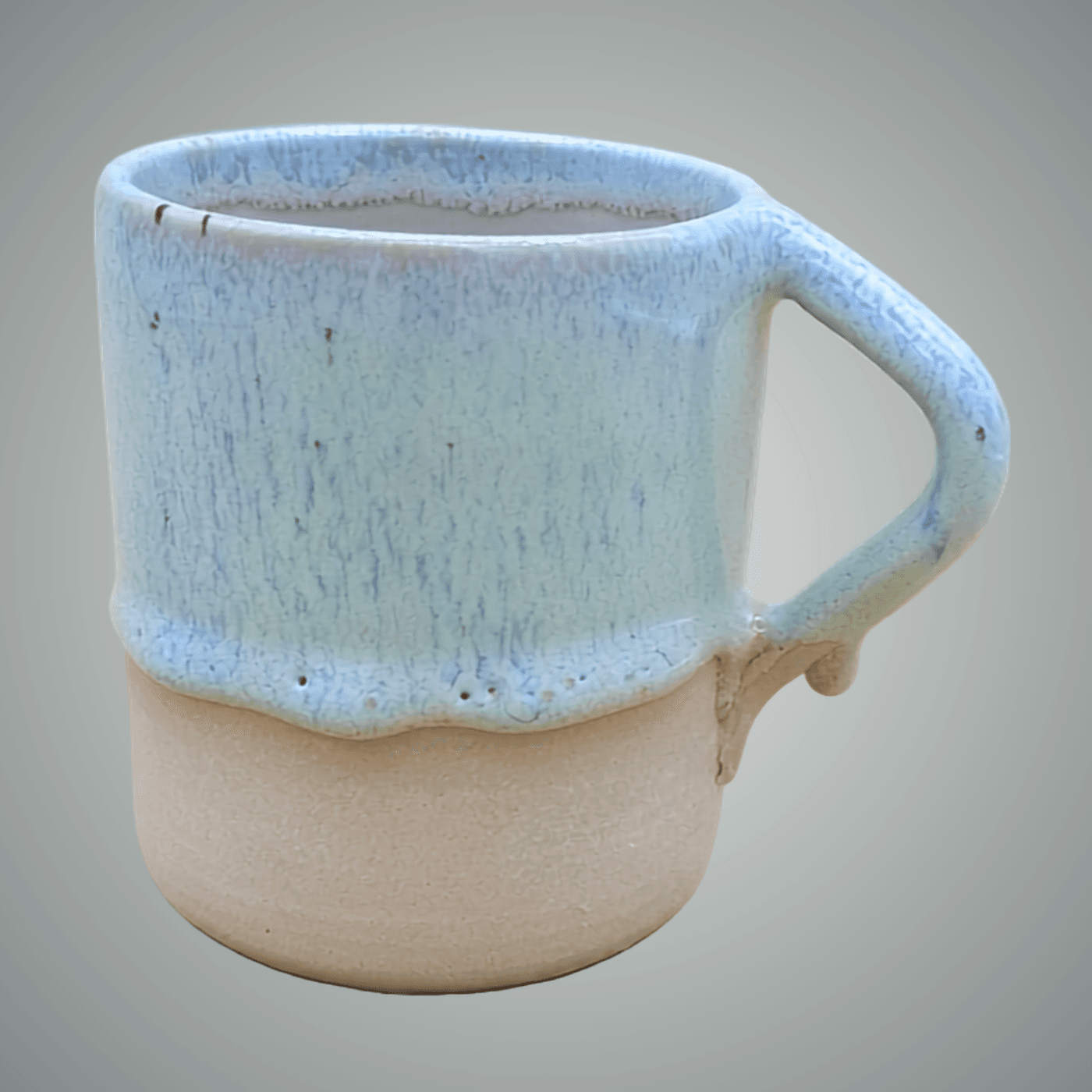 Handmade wheel-thrown stoneware cup with soft blue drip glaze and unglazed base. Geometric angular handle. One of a kind by ceramist Przemyslaw Golebiewski, Berlin.